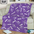 Purple lacrosse throw blanket spread across a sofa with repeating sticks, helmets, and balls