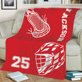 Red lacrosse blanket displayed on a couch with white helmet, stick, and sports graphics