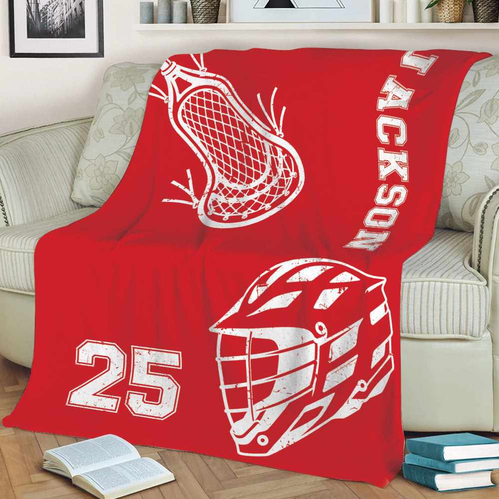 Red lacrosse blanket displayed on a couch with white helmet, stick, and sports graphics