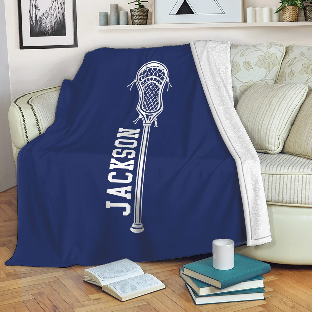 Blue lacrosse throw blanket draped over a sofa with a white lacrosse stick graphic