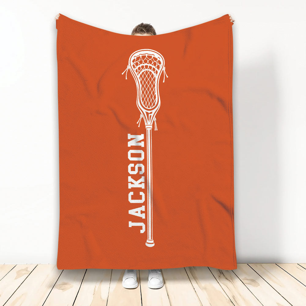 Orange lacrosse blanket displayed vertically with a centered white lacrosse stick design
