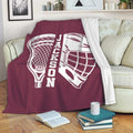 Maroon lacrosse throw blanket draped over a sofa with matching stick and helmet artwork