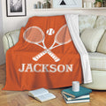 Orange tennis throw blanket featuring crossed racquets and tennis ball artwork on a living room sofa