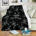 Black golf throw blanket draped over a sofa with repeating crossed clubs and golf ball design