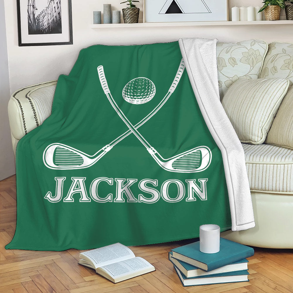 Green golf throw blanket with crossed clubs and golf ball displayed on a living room sofa