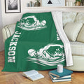 Green swimming blanket draped over a sofa with white swimmer artwork and bold graphic accents
