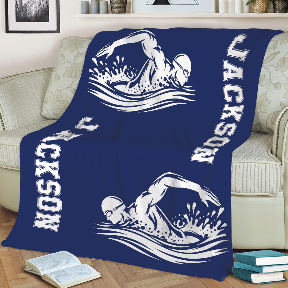 Navy swimming blanket displayed on a sofa with large white swimmer silhouettes