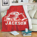 Red football throw blanket with helmet and football artwork displayed on a living room sofa