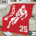 Red football throw blanket displayed on a sofa with dynamic player artwork and bold white sports graphics