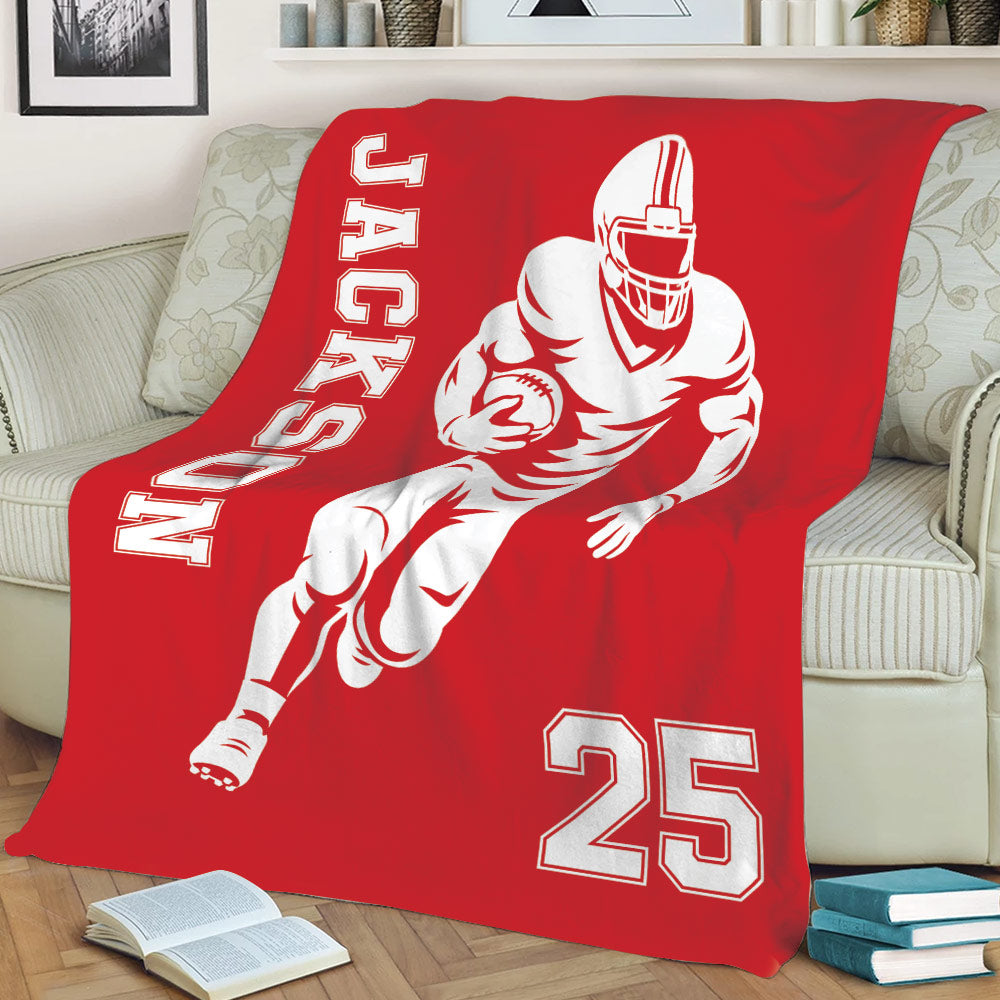 Red football throw blanket displayed on a sofa with dynamic player artwork and bold white sports graphics