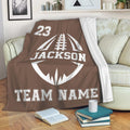 Brown football throw blanket draped over a sofa with bold white sports artwork