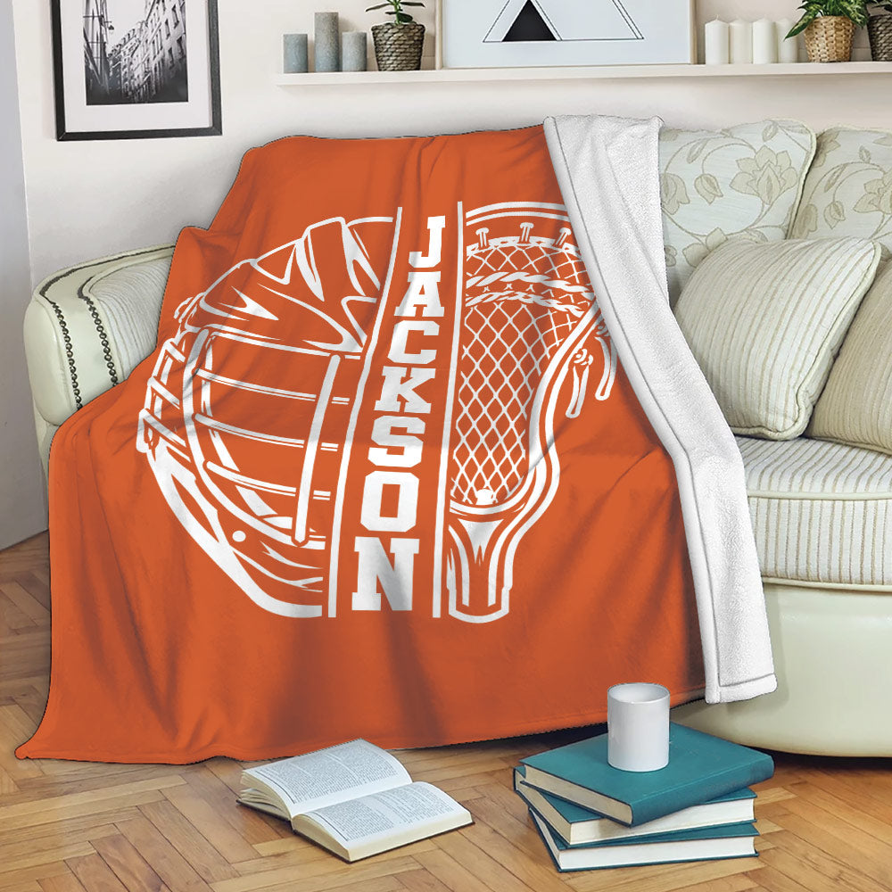 Orange lacrosse blanket draped over a sofa with a bold white helmet and stick design