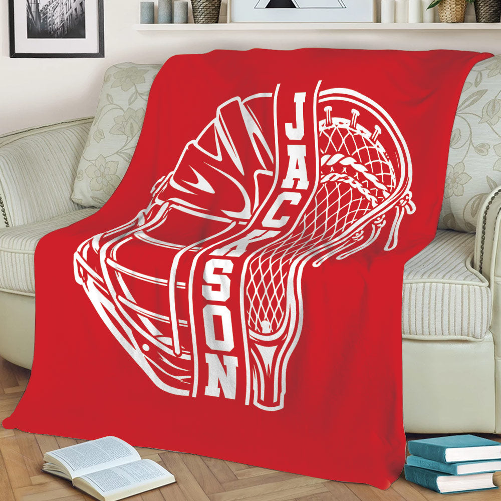 Red lacrosse blanket styled on a couch with an oversized white helmet and stick graphic