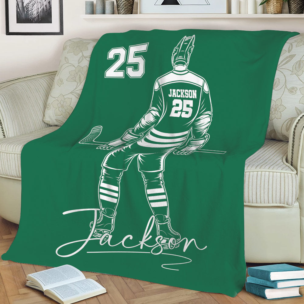 Green hockey throw blanket spread across a sofa with a seated player illustration and hockey stick