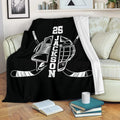 Black hockey blanket draped over a sofa with skate, helmet, and crossed hockey sticks design