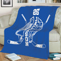 Blue hockey blanket styled on a sofa with skate, helmet, and crossed hockey stick artwork