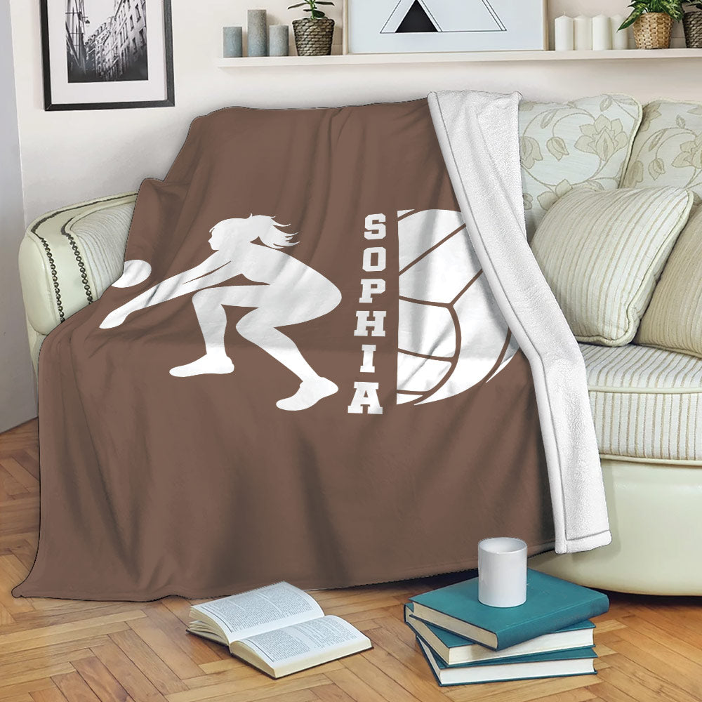 Brown volleyball blanket draped over a sofa, featuring a white volleyball player silhouette and ball design
