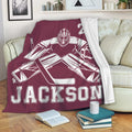 Hockey goalie blanket draped over a sofa with bold maroon sports artwork for a fan lounge