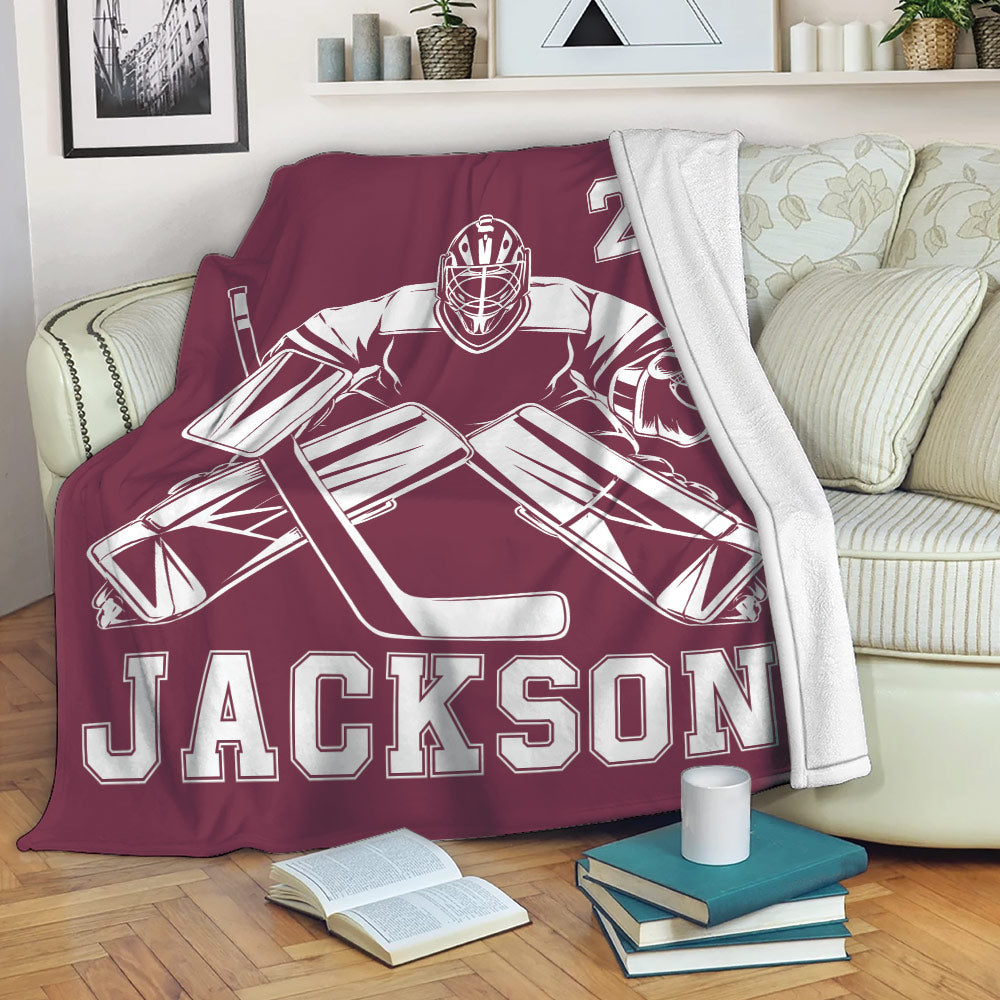 Hockey goalie blanket draped over a sofa with bold maroon sports artwork for a fan lounge