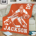 Orange hockey goalie throw blanket displayed across a sofa with high contrast sports artwork