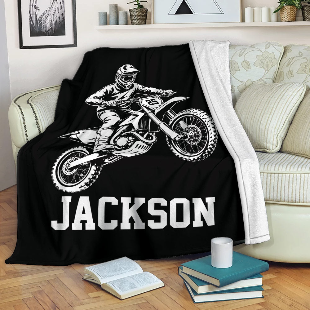Black motocross throw blanket draped over a sofa with dynamic dirt bike rider artwork