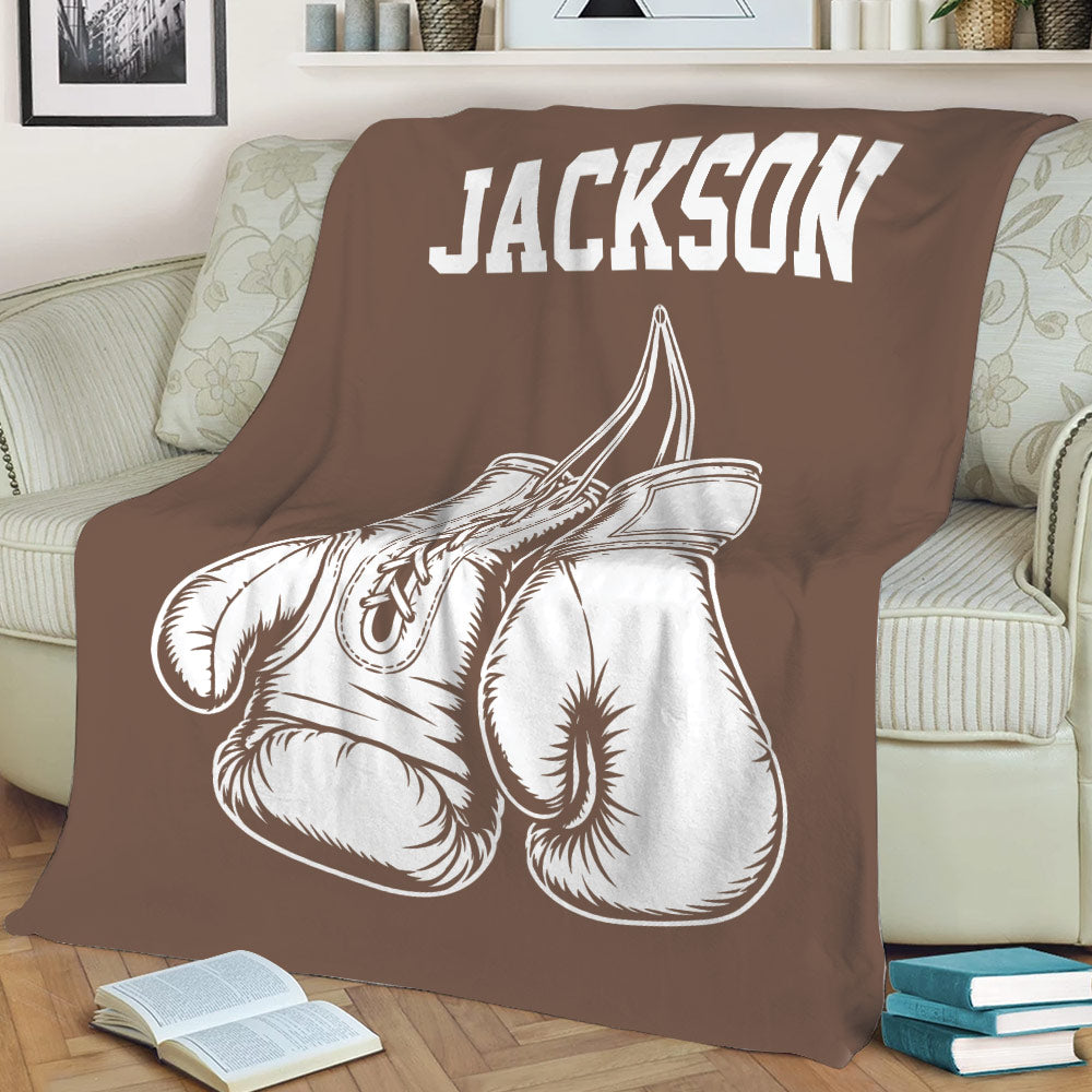 Brown boxing throw blanket displayed on a couch with prominent illustrated boxing gloves