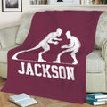 Maroon wrestling blanket displayed on a sofa with large white grappler artwork