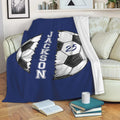 Blue soccer throw blanket displayed across a sofa with split soccer ball artwork and bold vertical design