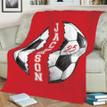 Red soccer throw blanket draped over a sofa with large split soccer ball artwork