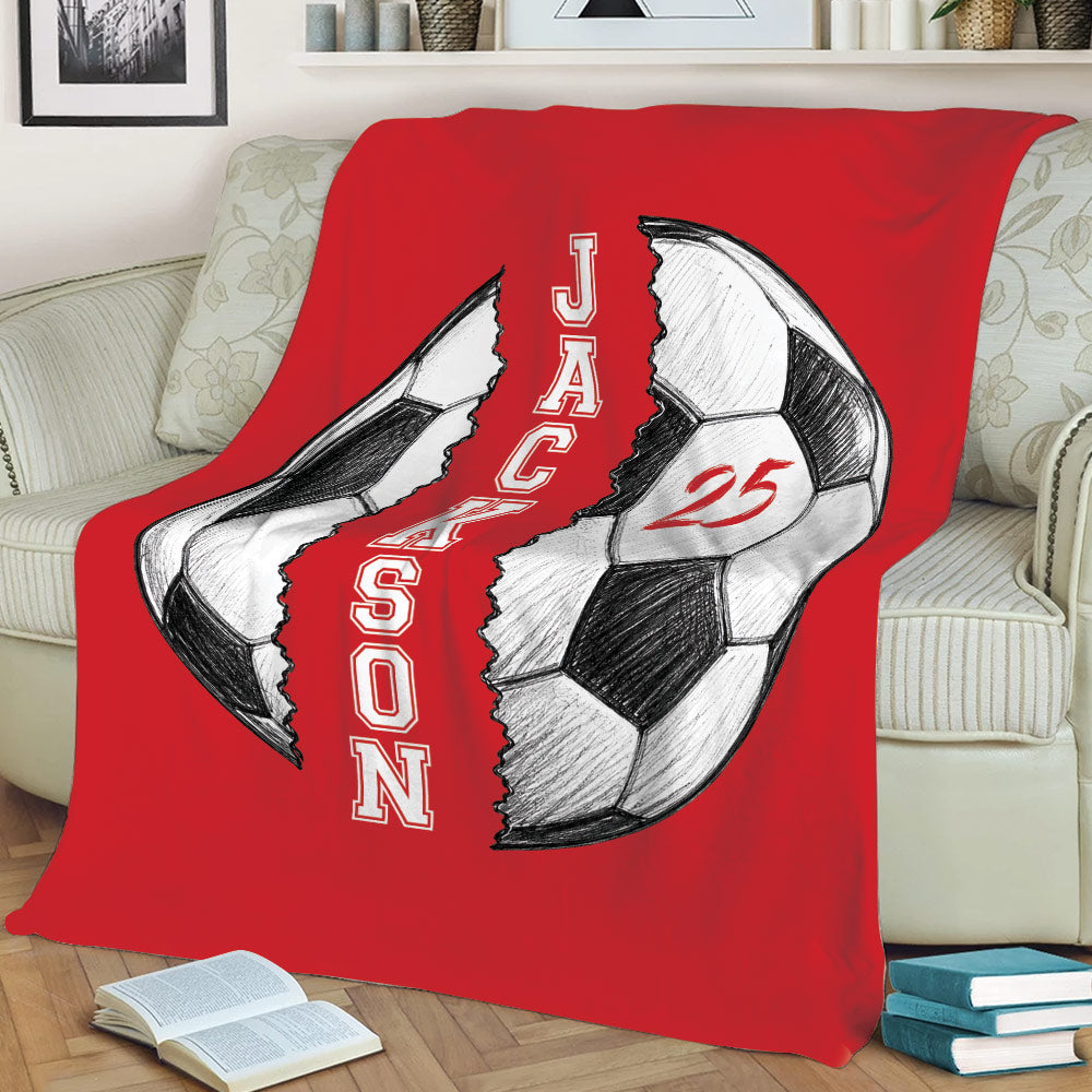 Red soccer throw blanket draped over a sofa with large split soccer ball artwork