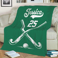 Green hockey blanket displayed on a sofa with crossed sticks and ball artwork