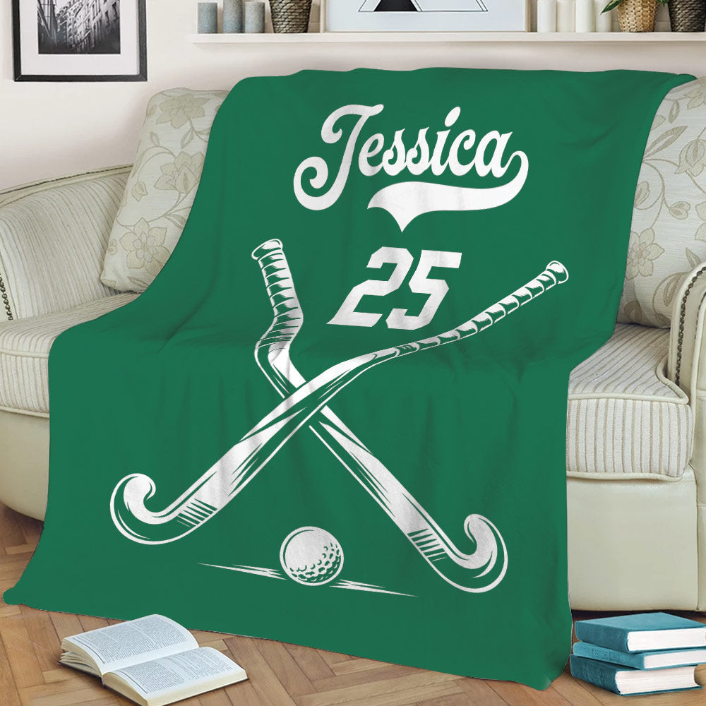 Green hockey blanket displayed on a sofa with crossed sticks and ball artwork