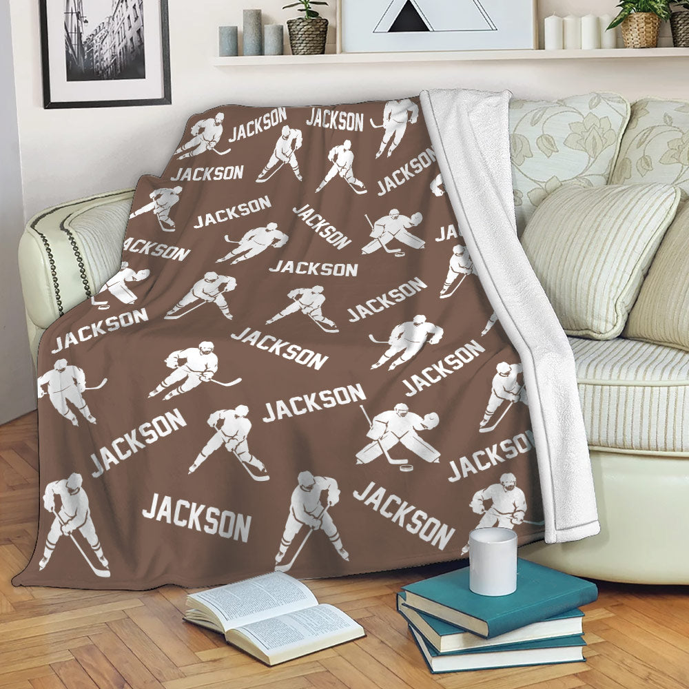 Brown hockey throw blanket draped over a sofa with repeating ice hockey player artwork