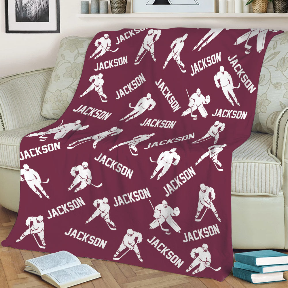 Maroon hockey throw blanket displayed on a sofa with repeating player and stick artwork