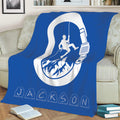 Blue rock climbing blanket styled on a sofa with bold white climber, mountain, rope, and carabiner artwork