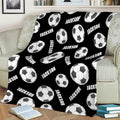 Black soccer throw blanket styled over a sofa with scattered soccer ball artwork