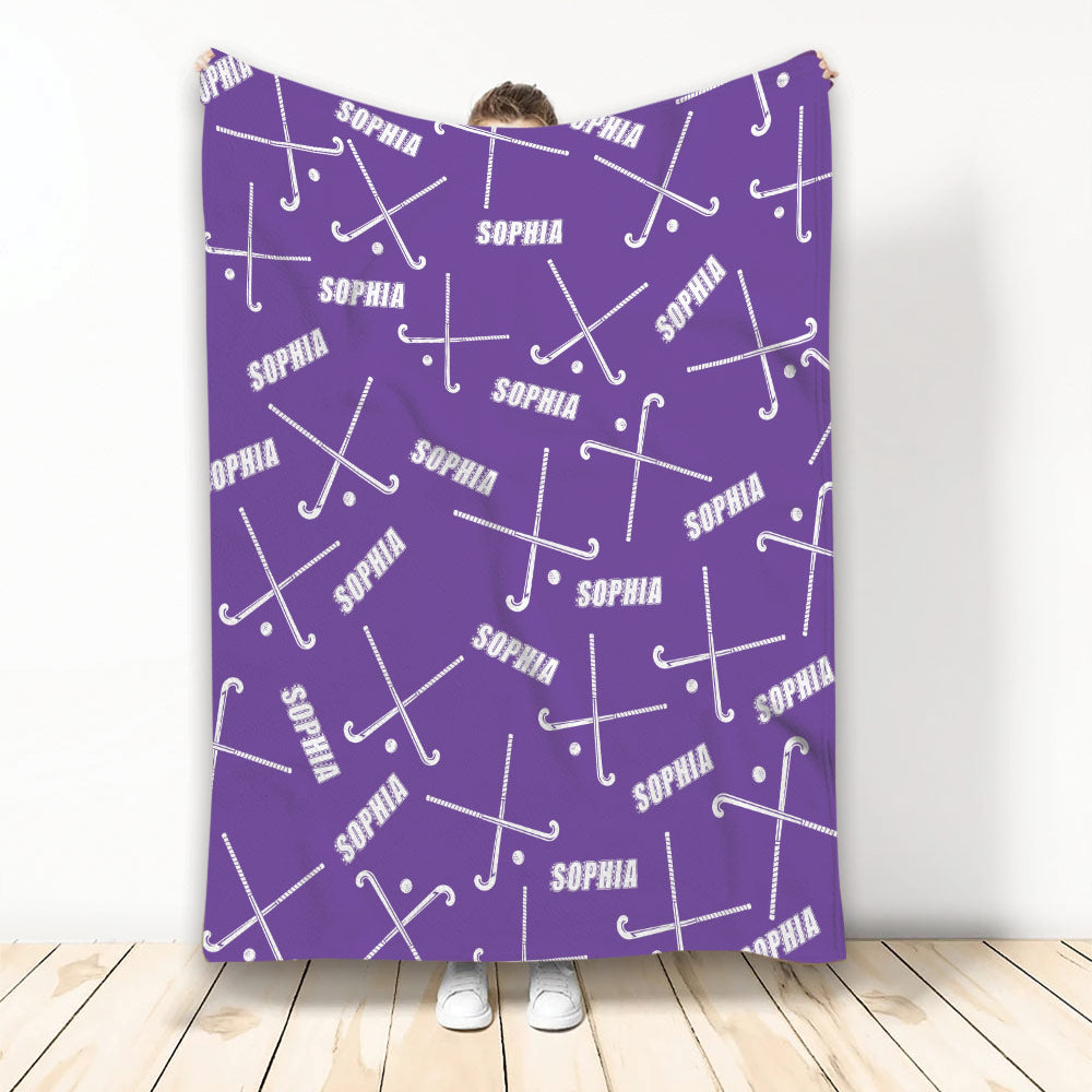 Purple hockey blanket displayed upright with white hockey sticks and pucks in an all-over pattern