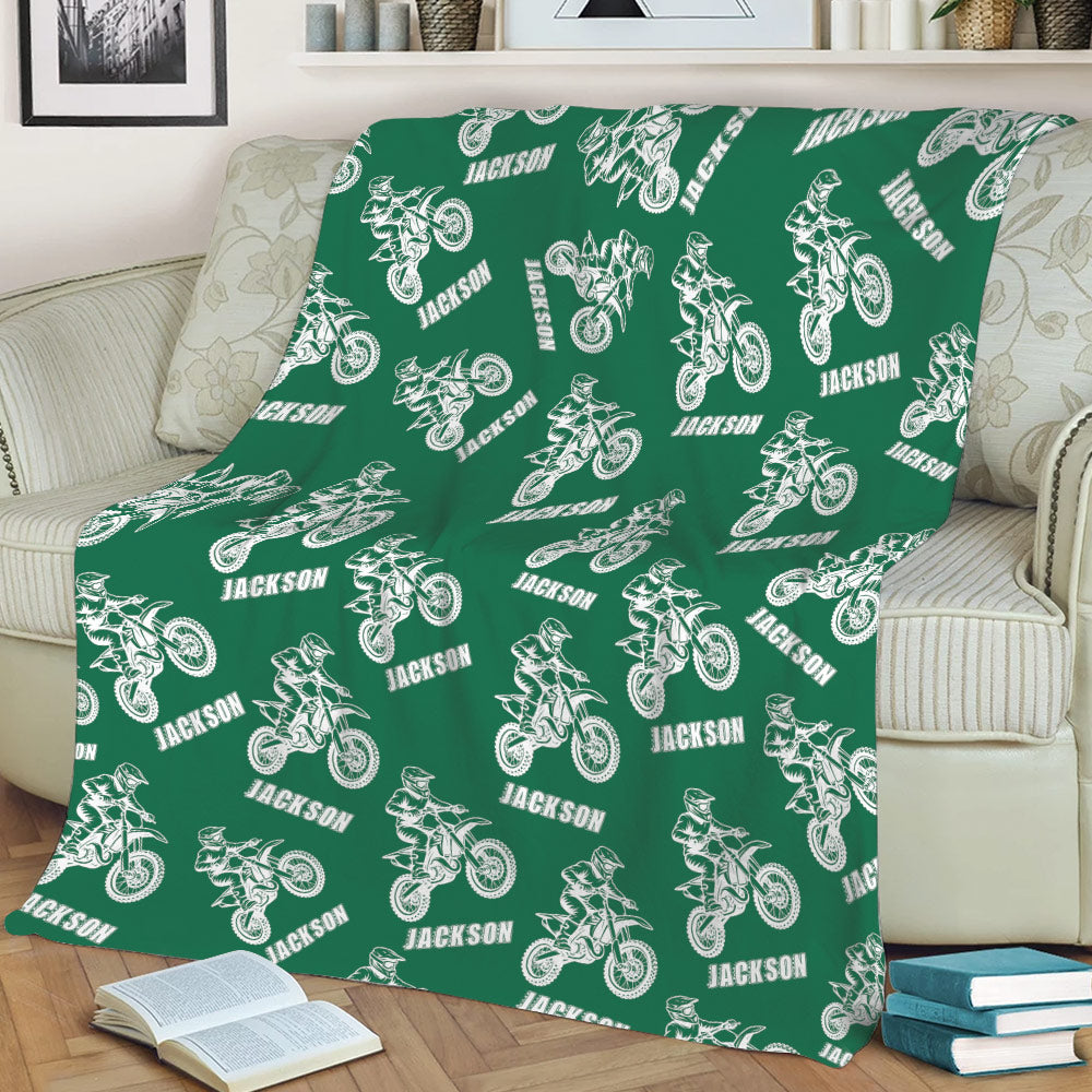Green motocross throw blanket draped over a sofa with repeated dirt bike illustrations