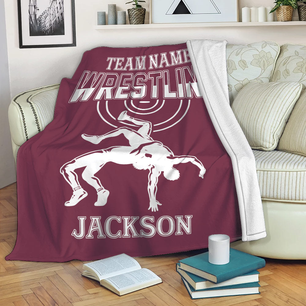 Maroon wrestling throw blanket draped over a sofa with bold lettering and dynamic grappling artwork