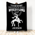Black wrestling blanket displayed upright with white varsity lettering and an illustrated wrestling takedown