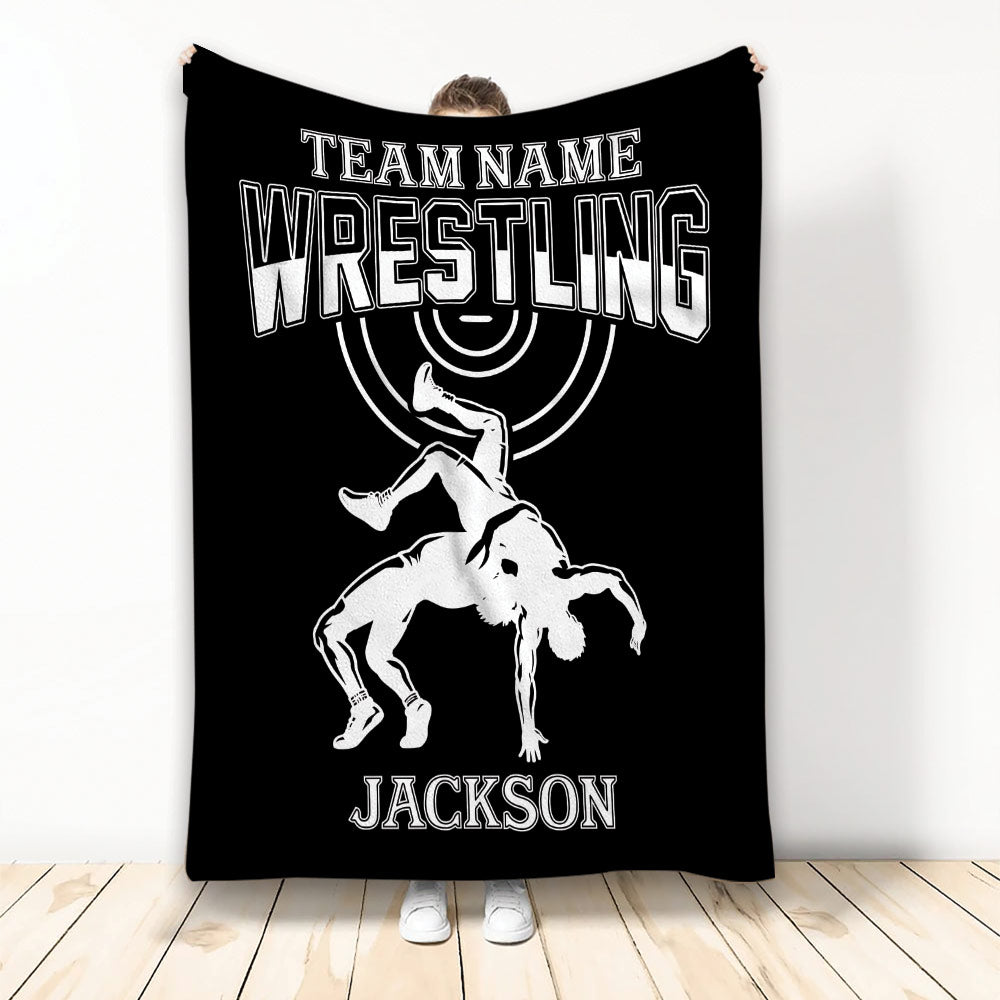 Black wrestling blanket displayed upright with white varsity lettering and an illustrated wrestling takedown