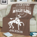 Close view of a brown wrestling throw blanket on a couch with bold lettering and grappling artwork