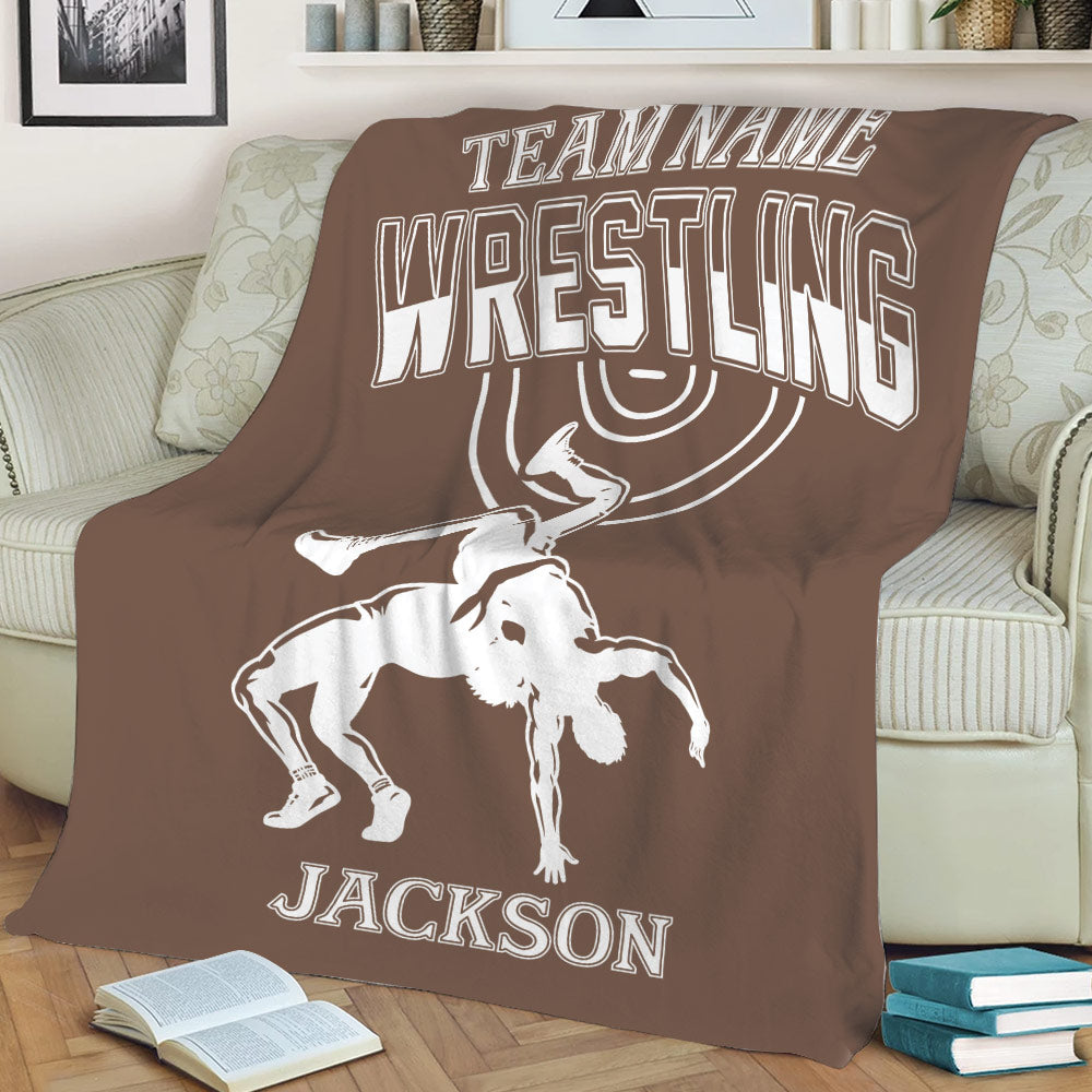 Close view of a brown wrestling throw blanket on a couch with bold lettering and grappling artwork