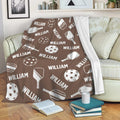 Brown pickleball blanket draped over a sofa with paddle and ball artwork for cozy lounging