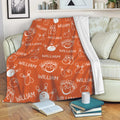 Orange bowling throw blanket draped over a sofa with repeating bowling ball and pin artwork
