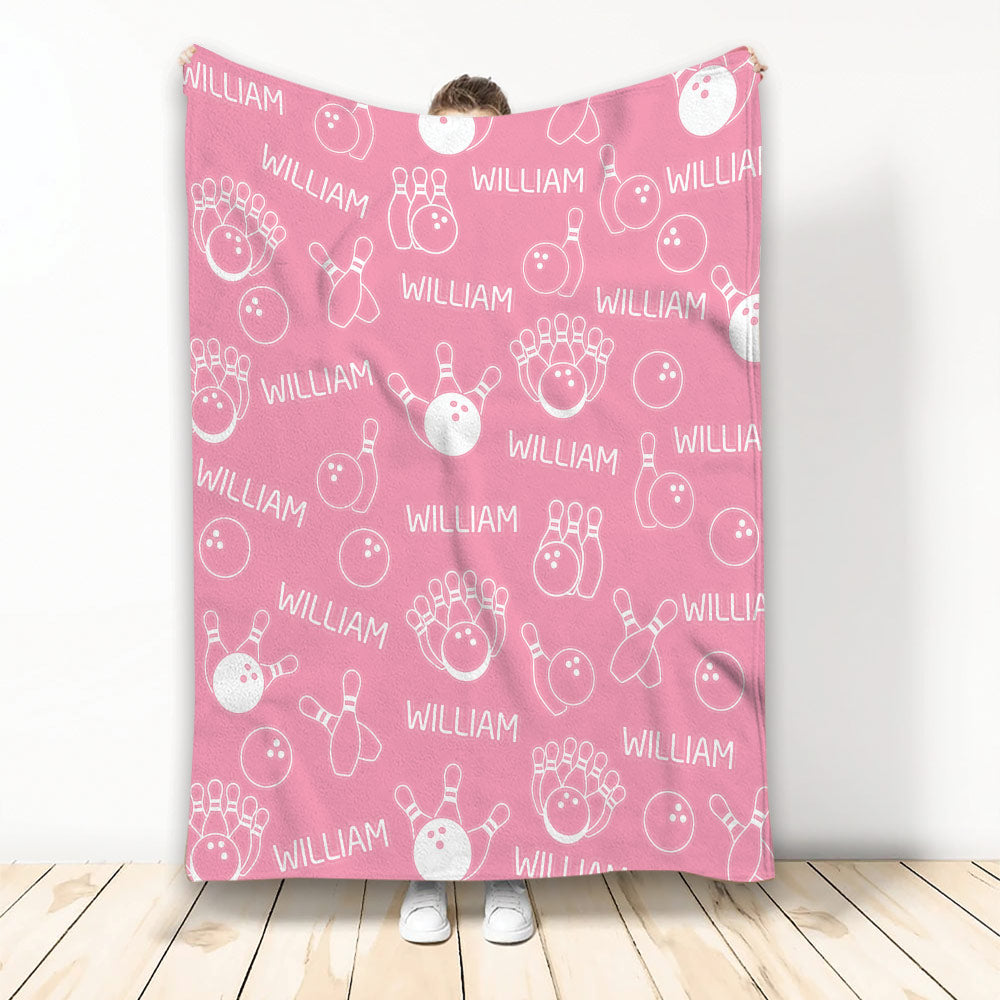 Pink bowling blanket displaying a playful repeating pattern of bowling balls, pins, and strikes