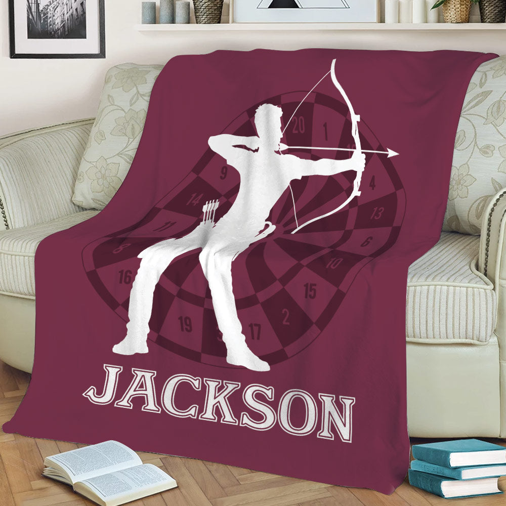 Maroon archery blanket displayed on a sofa with dynamic archer silhouette and target design