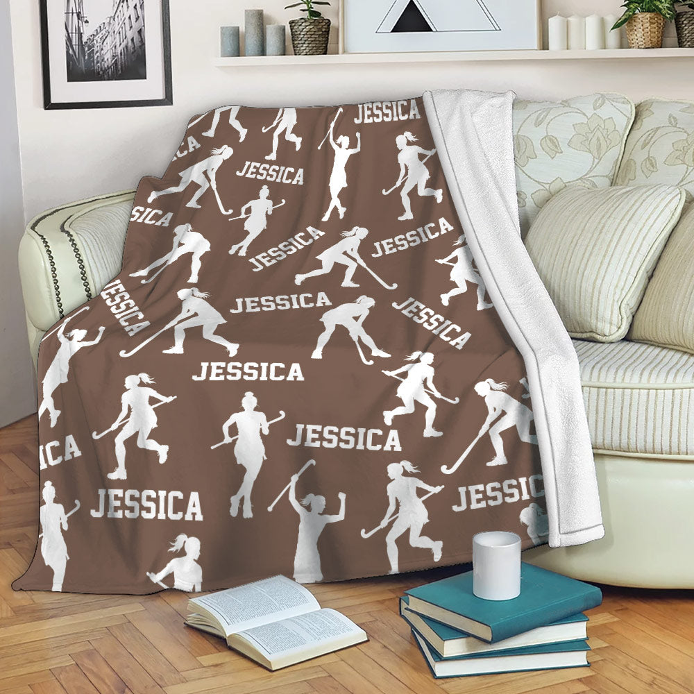 Brown hockey throw blanket styled on a sofa with repeating white player silhouettes and hockey sticks