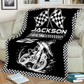 Black motocross blanket displayed on a sofa with dirt bike and racing flag artwork