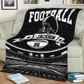 Black football blanket draped over a sofa with stadium field and helmet artwork